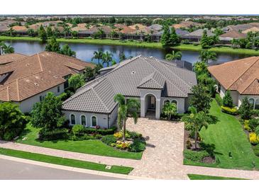 Stunning waterfront home with lush landscaping, tile roof, and brick paver driveway at 16628 Berwick Ter, Lakewood Ranch, FL 34202