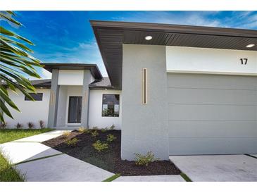 Modern home featuring a gray garage door, manicured landscaping, and stylish exterior lighting at 350 Bucknell Rd, Venice, FL 34293