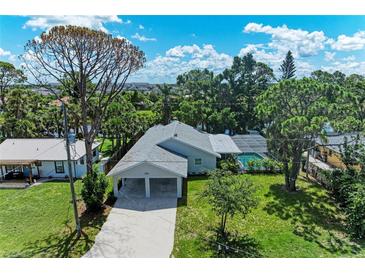Inviting single-story home with a carport, lush greenery, and sparkling pool view at 2400 Lake Shore Dr, Nokomis, FL 34275