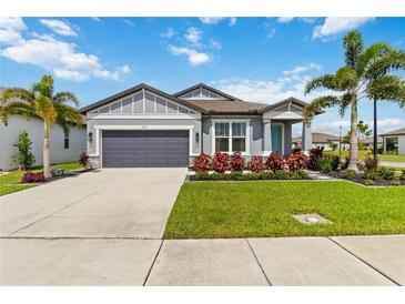 Charming single-story home with a manicured lawn, palm trees, and a gray two car garage at 3602 Quiet Dr, Sarasota, FL 34240