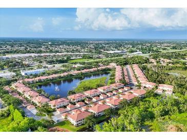 Beautiful aerial view of townhomes with a central lake featuring a fountain and lush landscaping at 4210 Vicenza Dr # D25, Venice, FL 34293