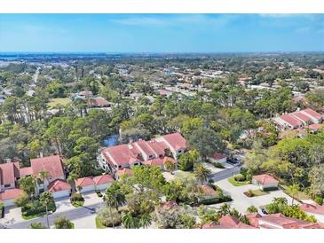 Expansive aerial view of community with mature trees, serene pond, and well-maintained red tile roofs at 7674 Fairway Woods Dr # 1605, Sarasota, FL 34238