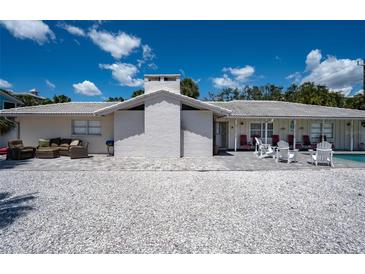 Charming single-story home with a white brick chimney, comfortable patio furniture, and a shell-covered yard at 1201 Big Oak Ln, Sarasota, FL 34242