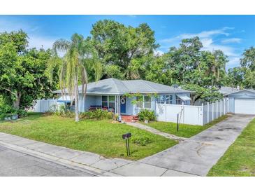 Charming single-story home with a well-manicured lawn, palm tree, and a white picket fence at 401 N Jefferson Ave, Sarasota, FL 34237