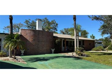 Charming single-story home with a brick accent wall, mature landscaping, and a green driveway at 4158 Prudence Dr, Sarasota, FL 34235