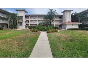 Well-maintained condo building with lush landscaping, palm trees, and a welcoming walkway at 6507 Stone River Rd # 302, Bradenton, FL 34203
