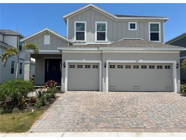 Charming two-story home with gray siding, dual garage and a brick paver driveway at 931 Signet Dr, Apollo Beach, FL 33572