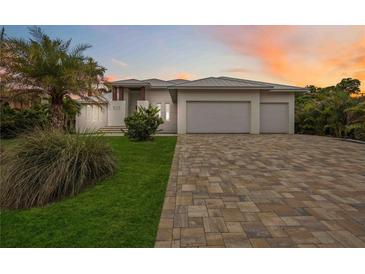 A beautiful home with a three car garage and paver driveway is surrounded by lush landscaping at 103 Graham Se St, Port Charlotte, FL 33952