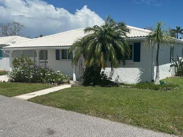 Charming white home featuring lush landscaping and vibrant plants creating inviting curb appeal at 675 El Centro # 675, Longboat Key, FL 34228