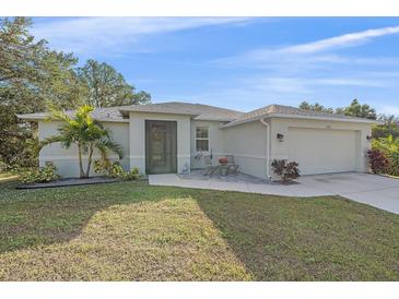 Charming one-story home with a well-manicured lawn, complemented by a beautiful palm tree and a cozy seating area near the entryway at 8755 Dolomite Ave, North Port, FL 34287