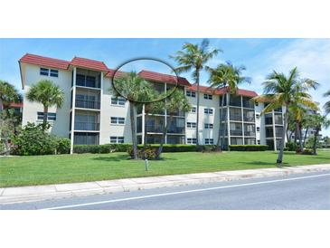 A well-maintained condo building with balconies, red roof, lush landscaping, and palm trees at 925 Beach Rd # 408, Sarasota, FL 34242