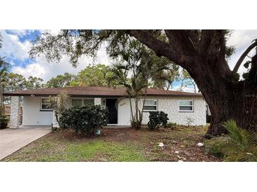 Charming single-story home featuring a textured exterior and a well-maintained front yard with mature trees at 4661 Linwood St, Sarasota, FL 34232