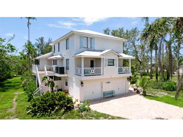 Charming two-story coastal home with a white exterior, multiple balconies, and a spacious driveway at 9403 9Th Nw Ave, Bradenton, FL 34209
