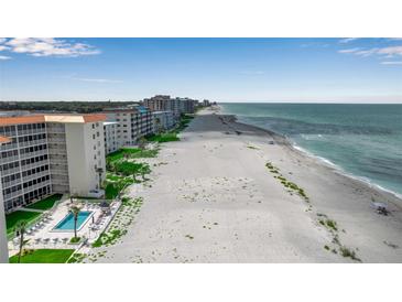 Expansive beachside condos, showcasing pristine sandy shoreline and turquoise ocean views under a partly cloudy sky at 1150 Tarpon Center Dr # 1-C 103, Venice, FL 34285