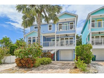 Charming blue two-story beach house with a brick driveway and tropical landscaping at 202 75Th St, Holmes Beach, FL 34217