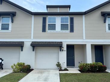 Two-story townhome with beige siding, a white garage door, and a blue front door at 5812 Ocean Isle Dr, Nokomis, FL 34275