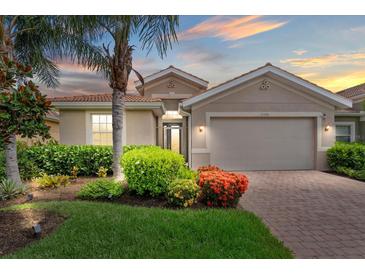 Charming home featuring a beautiful landscaped yard with mature palm trees and a brick driveway at 11550 Blackfin St, Venice, FL 34292