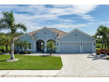 Charming single-story home featuring a lush lawn, mature palms, a paver driveway, and a three-car garage at 15808 42Nd E Gln, Parrish, FL 34219