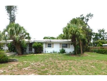 Cozy single-story home featuring a white exterior and a lush lawn with mature palm trees at 2711 Kilgore Pl, Sarasota, FL 34235