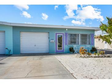 Charming home with a light blue exterior, white garage door, and vibrant purple door and shutter accents at 441 62Nd St, Holmes Beach, FL 34217