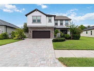 Beautiful two-story home with a stone facade and a well-maintained lawn and a brick driveway at 731 116Th Ne Ct, Bradenton, FL 34212
