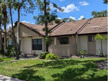 Inviting exterior view of a charming townhome with manicured lawn, mature landscaping and beige facade at 5231 Brassy Loop, North Port, FL 34287