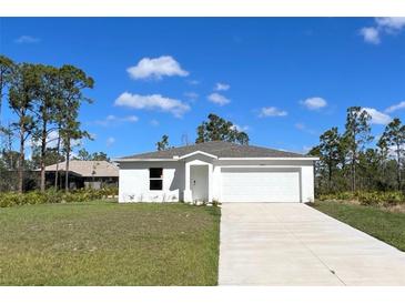 Charming single-story home with a two-car garage and a well-manicured front lawn under a bright blue sky at 13084 Parham Ave, Port Charlotte, FL 33953