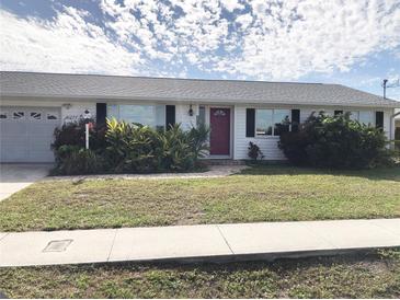White house with red door, two-car garage, and landscaping at 21277 Edgewater Dr, Port Charlotte, FL 33952