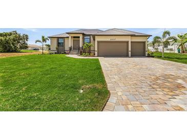 Single-story home with two-car garage, paver driveway, and lush lawn at 24237 San Lucas Ln, Punta Gorda, FL 33955