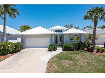 Single-story home with white exterior, attached garage and lush landscaping at 15 Windward Pl, Placida, FL 33946