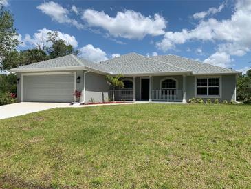 Charming single-story home with a well-manicured lawn, attached garage, and inviting front porch at 17184 Wintergarden Ave, Port Charlotte, FL 33948