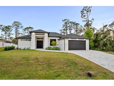 Beautiful one-story home with a modern design, manicured lawn, and a two-car garage on a sunny day at 5815 Casanova Ave, North Port, FL 34291