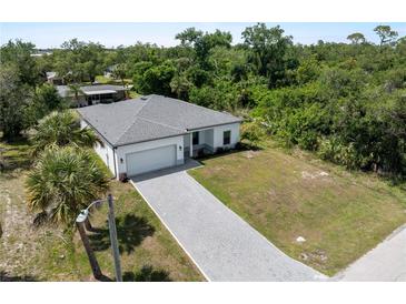 New construction home featuring a paver driveway, attached garage and tropical landscaping at 2049 Delta St, Port Charlotte, FL 33952