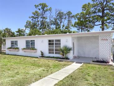 Charming Ranch style home with white brick facade and well-manicured lawn at 22239 Midway Blvd, Port Charlotte, FL 33952