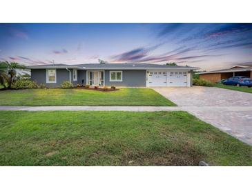 Gray house with white garage doors, landscaping, and paved driveway at 2309 Conway Blvd, Port Charlotte, FL 33952