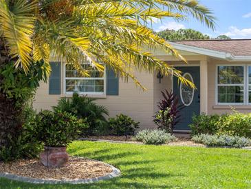 Charming house exterior with landscaped yard and teal door at 1191 Manor Rd, Englewood, FL 34223
