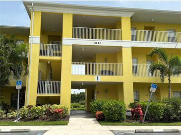 Two-story yellow building with balconies and landscaping at 2140 Heron Lake Dr # 204, Punta Gorda, FL 33983