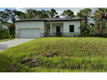 Single-story home with attached garage and grassy lawn at 13460 Tolman Ave, Port Charlotte, FL 33953