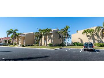 Tan condo building with palm trees and parking at 3251 White Ibis Ct # A4, Punta Gorda, FL 33950