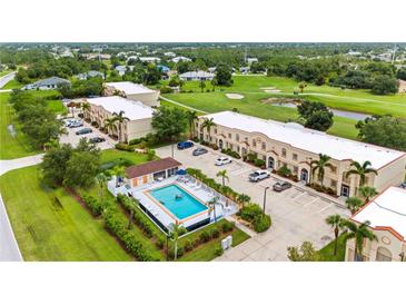 Aerial view of a community with multiple buildings, parking, and a swimming pool at 1186 Rio De Janeiro Ave # 104, Punta Gorda, FL 33983