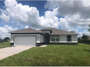 One-story home with a white and gray exterior, two-car garage, and a well-maintained lawn at 16216 Minorca Dr, Punta Gorda, FL 33955