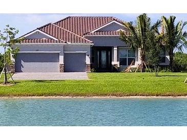 Charming single-story home with a well-manicured lawn and serene water view at 15240 Spanish Point Dr, Port Charlotte, FL 33981
