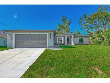 Newly built home with a gray garage door and a well-manicured lawn at 4582 Enid Ln, North Port, FL 34288