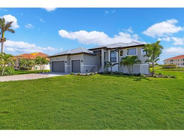 Beautiful two-story home featuring a well-manicured lawn, complemented by lush landscaping and a two-car garage at 24051 Pyramid Way, Punta Gorda, FL 33955
