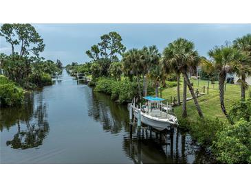 Scenic waterfront view featuring a private boat dock, lush tropical landscaping, and serene canal access at 2256 Auburn Blvd, Port Charlotte, FL 33948