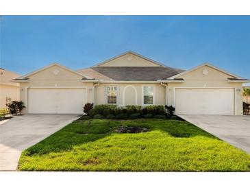 Front view of a charming tan house with two garages at 7457 W Lenox Cir, Punta Gorda, FL 33950