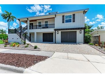 Two-story coastal home featuring a 2-car garage, covered balcony, and well-manicured landscaping at 611 W Olympia Ave, Punta Gorda, FL 33950