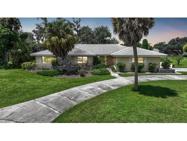 Single-story home with a tiled roof, palm trees, and a landscaped lawn at 4041 Michel Tree St, Port Charlotte, FL 33948
