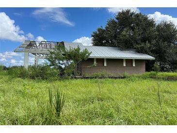 Brick home with damaged roof and boarded windows, situated on a grassy lot at 31840 Washington Loop Rd, Punta Gorda, FL 33982