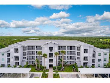 Aerial view of a modern apartment building with parking and tropical landscaping at 14131 Heritage Landing Blvd # 838, Punta Gorda, FL 33955